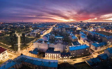 Fototapeta na wymiar Aerial view of busy city in colorful sunset and street lights. Drone shot of Riga city. 