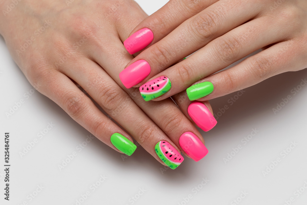 Wall mural Summer pink and light green manicure with painted watermelons. Vacation manicure. Close-up on a white background. Acid colors of nails. Themed nails.