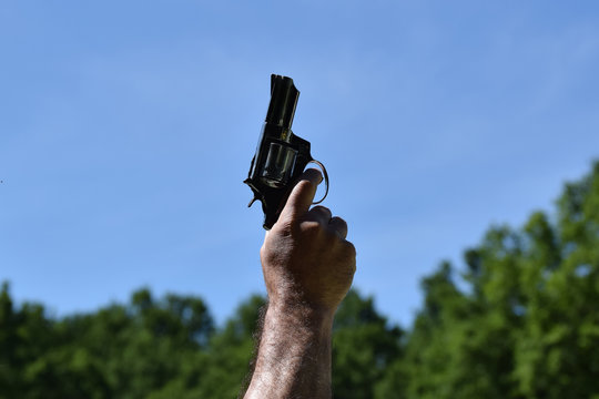 A man pointing to a clear blue sky with a gun before starting a race