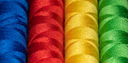 Vertical cones of bright colored sewing thread in Blue red yellow and green representing Jung personality types - obrazy, fototapety, plakaty