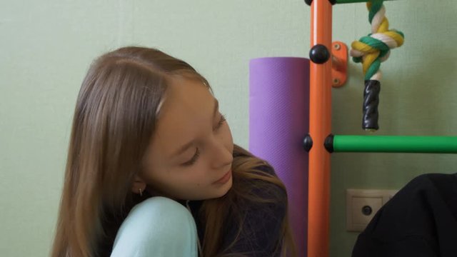 Thoughtful young girl sitting in playroom. Pensive preadolescent child talking with someone. Thinking concept