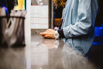 Close-up of woman holding mobile phone at counter of street restaurant