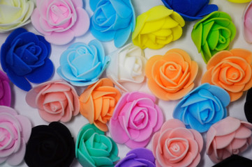 artificial roses of different colors lie on a white background. rose - queen of flowers