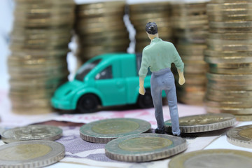 mimiature people with coins and car. Miniature businessman walking through a toy car. Concept of financial, retail, money saving and business. Turkey car price infilation. Car mortgage related