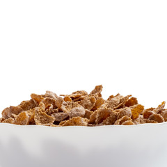 Natural whole grain wheat flakes in white bowl. Healthy breakfast concept. Plate with multigrain flakes on white background