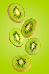 Falling green kiwi isolated on green background.
