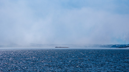 Fog rises above the sea or river and closes the shore