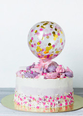 Happy birthday cake decorated with marshmallows, sweets and a balloon.