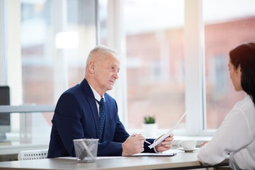 Side view portrait of successful senior businessman interviewing young woman for job position in office, copy space