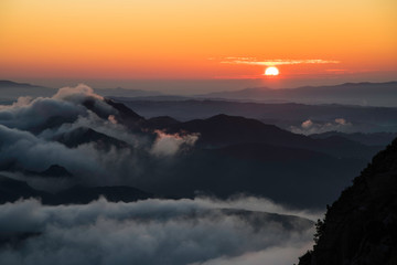 Image of mountains at sunrise with the first rays of the sun on the horizon with warm colors
