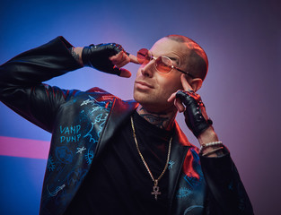 Creative, daring, tattooed, bald male rocker model posing in a studio for the photoshoot wearing...