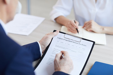 Close up of unrecognizable senior businessman signing contract agreement during meeting in office, copy space
