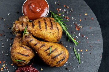 grilled chicken legs with red sauce on a stone surface