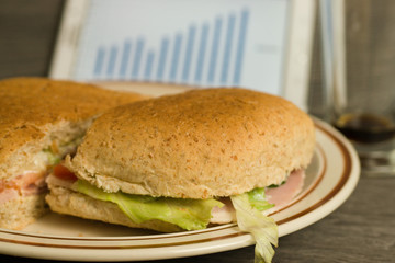 Tablet with financial graph and ham salad sandwich