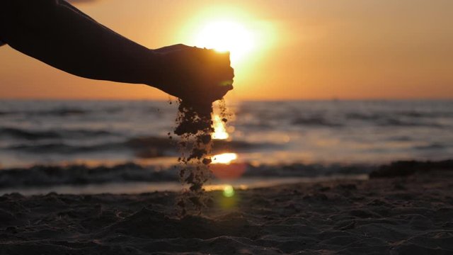 Sand as the time slips through your fingers. Little girl holding a sand sea background. Sand in your hands. Concept of vacation and trip to the sea.