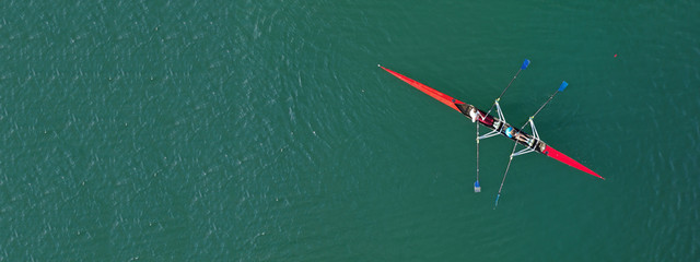 Aerial drone ultra wide photo of young athletes rowing in canoe competition in tropical lake with emerald waters