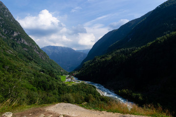 Fototapeta premium a landscape with mountains and a mountain river on a sunny day with cloudy sky in Norway.