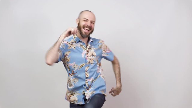 Happy bearded bald man having fun on white background. Joyful lucky tourist wearing hawaiian shirt.