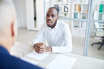 Portrait of contemporary African-American man answering questions to HR manager during job interview in office, copy space