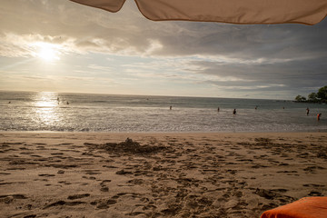 Obraz premium Rain on the beach under an umbrella with orange towel near by.