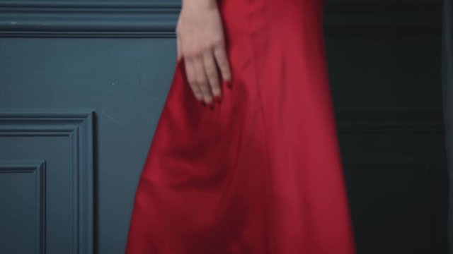 Beautiful brunette woman lady in a silk red dress evening make-up leans against a blue wall to bask in a luxurious life glamorous model style fashion jewelry tender skin youths attractive sexy female. Beautiful brunette woman lady in a silk red dress evening make-up leans against a blue wall to bask in a luxurious life glamorous model style fashion jewelry tender skin youths attractive sexy female.