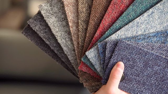 the man chooses the color of the new carpet according to the pattern book in the flooring shop