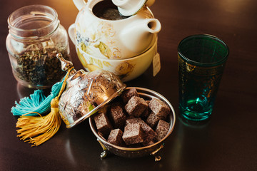 Obraz na płótnie Canvas Teapot, sugar, tea glasses and mint on a brown table