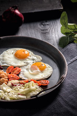 Close-up of sunny side up eggs with vegetables on dark background