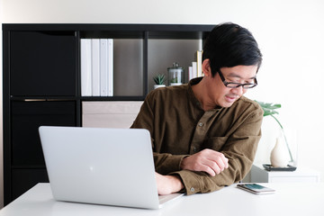Smart youngadult 40s asian man with eye glasses working on laptop or computer notebook in modern working space. office life and career.