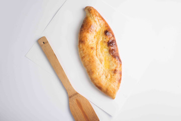 closed khachapuri pie served on a board on a white background