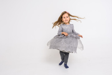 little fair-haired girl in a dress is spinning and dancing isolated on a white background