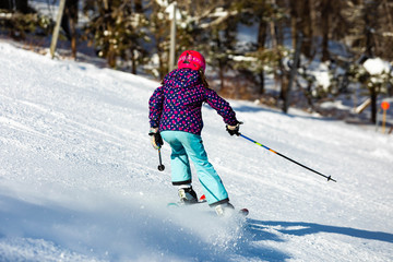 Skier girl performing slalom ride and having fun at resork in winter from the back