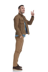 Side view of happy casual man pointing and smiling