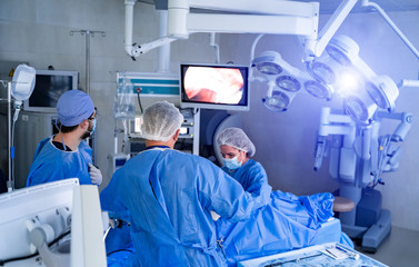 Team of surgeons performing operation in bright modern surgery room. Operating theatre. Modern...