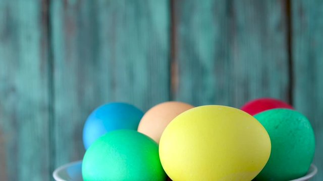 Colorful easter eggs in a basket revolve on a wooden background. Easter concept background.