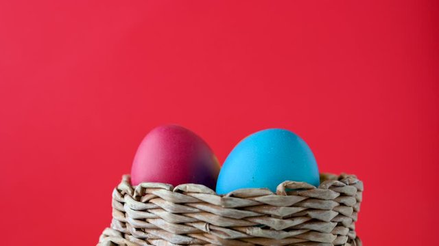 Colorful easter eggs in a basket rotate on a red background. Easter concept background.