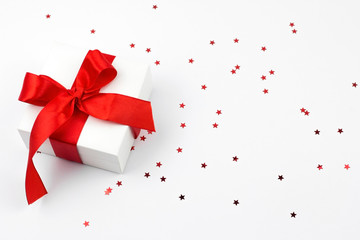 Present box with red bow on white wooden rustic surface. Festive picture made in flat lay style with place for text