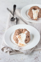 Chocolate cottage cheese dessert decorated with white chocolate glaze, coconut flakes and cocoa powder, light grey stone background. 