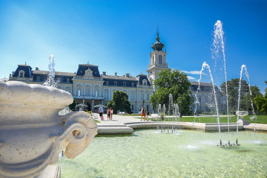 Festetics Palace behind beautiful gardens in Keszthely, Hungary on a clear sunny day. view of the palace and gardens, and some tourists people.