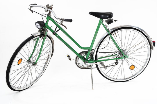 An old retro looking green vintage city bicycle for women, isolated o white background. Side view