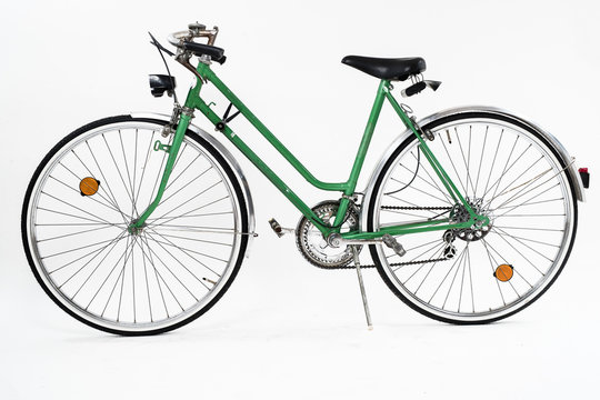An old retro looking green vintage city bicycle for women, isolated o white background. Side view