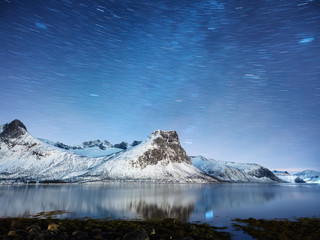 Fototapeta na wymiar Mountains and starry night sky, Senja islands, Norway. Reflection on the water surface. Winter landscape with night sky. Norway travel - image