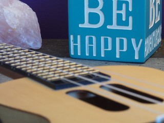 Ukulele Strings Close Up with a Be Happy Sign in Background