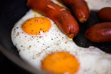 Bull's eye eggs fried in a pan with sausage