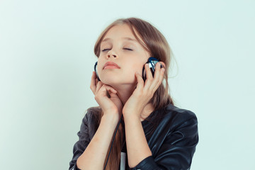 Happy cute smiling kid girl listening to music in her headphones