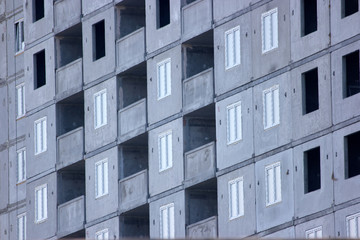 Facade of unfinished high-rise concrete building. Grey skyscraper close up.