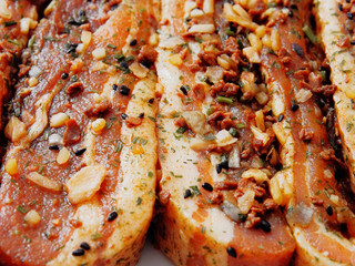 Serving of raw uncooked pork belly slices in soy marinade and herbs on a white plate Close up, Selective focus.