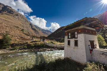 The Mountain landscape of Bhutan, the Paro Chu River beside the Paro - Thimphu Highway. A small Dzong on the fast flowing mountain river in the Himalayas. White clouds on a clear blue sky. 