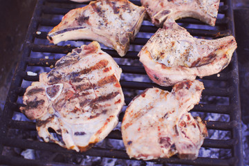 Close-up delicious grilled beef steaks with rib. Camping near the fire. Meat dish. Grill wire mesh. Healthy way of life, travel. Cooking, restaurant business concept. Anti vegan tasty meat.