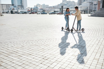 End your weekend by riding a vehicle. Friends using electric scooter on a sunny day